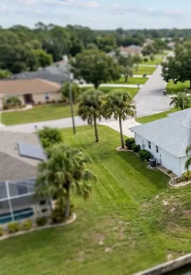 Example frame from an aerial video: rooftops, lawns, palms and a screened pool seen from above